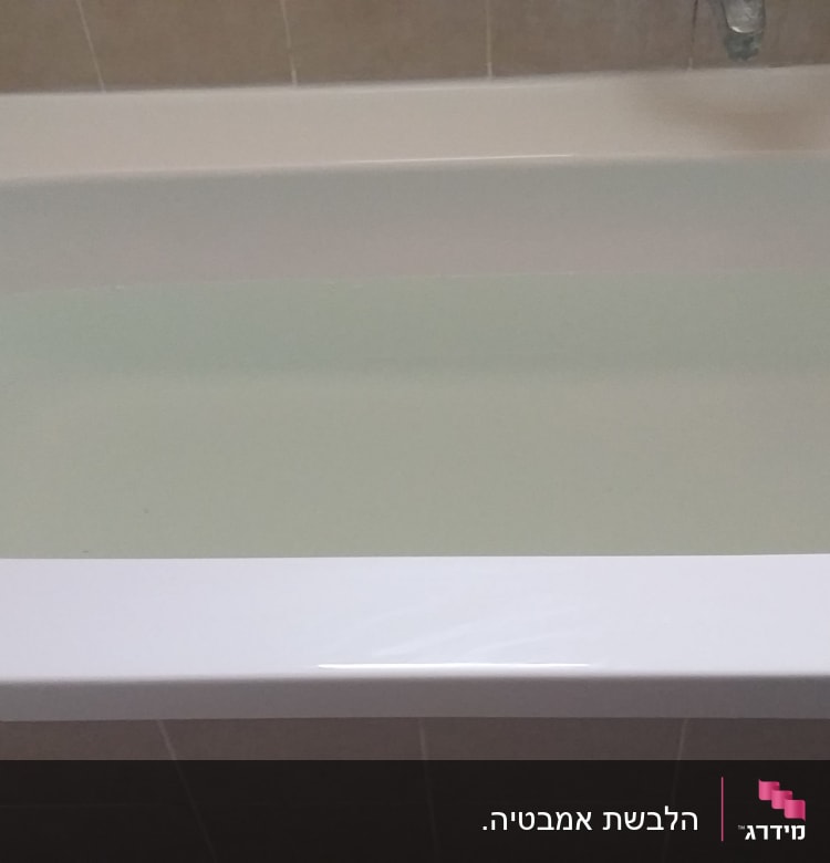 אמבטיה לבנה מלאה במים עם אריחים חומים מסביב